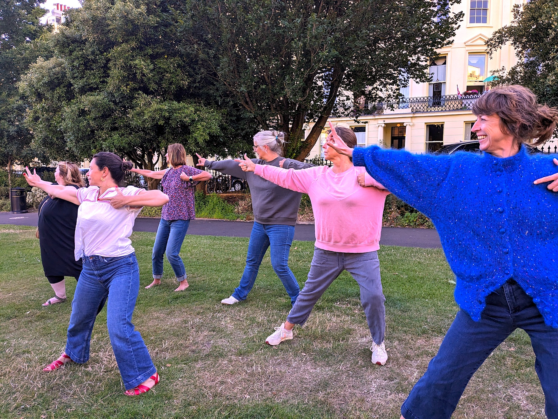 A private qigong class with a group of friends practising together outdoors on the grass at Brunswick Square, Brighton